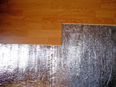 StarFlex-Produkte - Isolierung des Hauses: Dach, Wände, Boden - Foto zeigend die Anbringung von StarFlex® Floor unter den Teppich